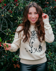 woman wearing an ivory sweater with a Paddington bear design