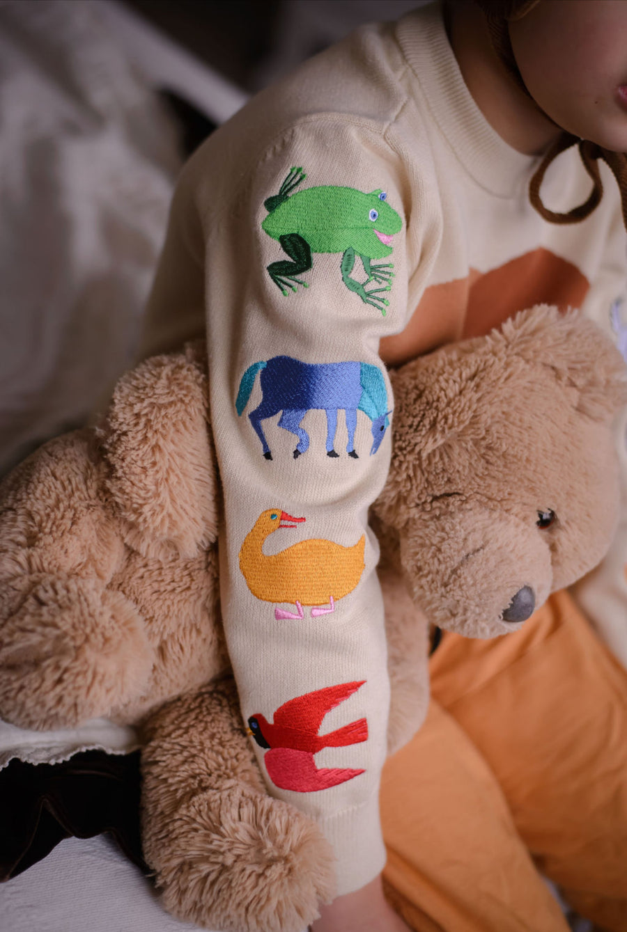 Close-up of a child's left sleeve featuring colorful embroidered animals