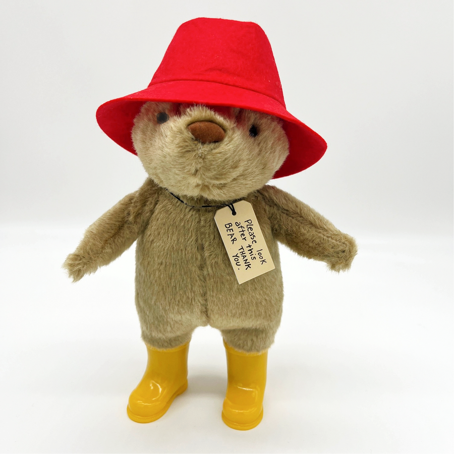 Plush Paddington Bear with a red hat, yellow boots, and a tag reading, "Please look after this BEAR. Thank you