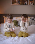 Two kids wearing Paddington Bear sweaters on a bed.