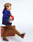 Child in Paddington Wool Toggle Coat, walking with suitcase and plush