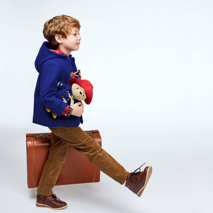 Child in Paddington Wool Toggle Coat, walking with suitcase and plush