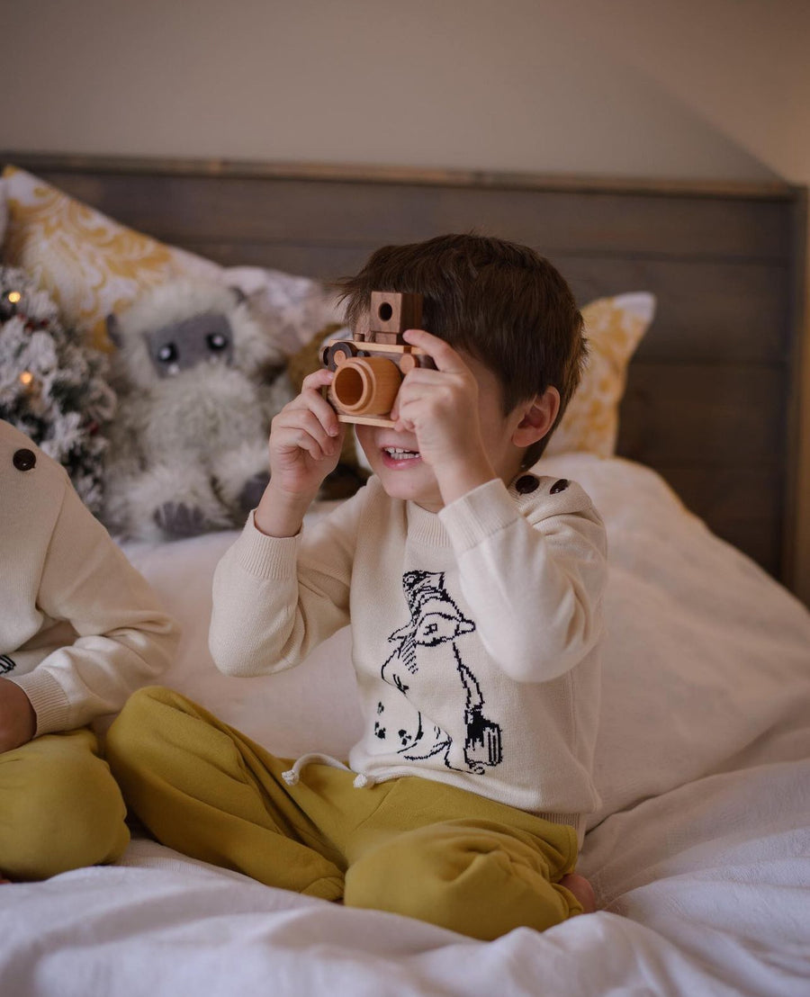 Child in a Paddington sweater holding a wooden camera