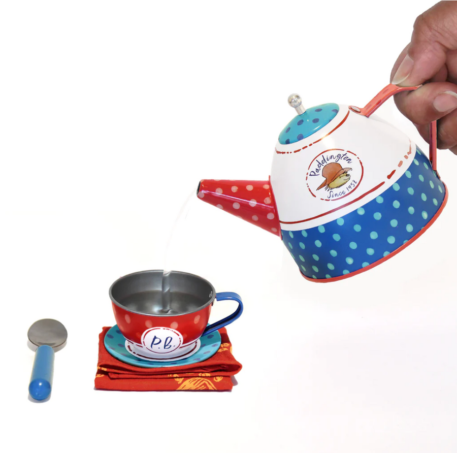 Hand pouring from Paddington-themed teapot into cup.