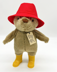 Plush bear with a red hat, yellow boots, and a tag reading, "Please look after this BEAR