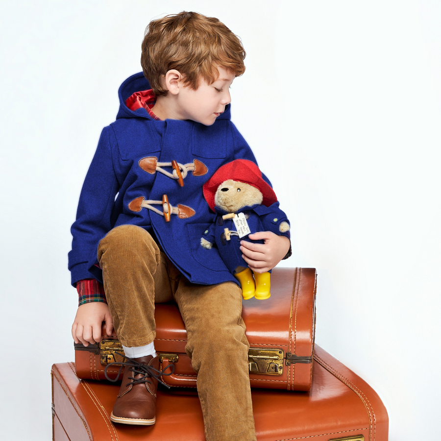 Boy in blue duffle coat with Paddington Bear plush