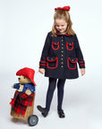 Girl in a navy coat pulling a Paddington Bear toy