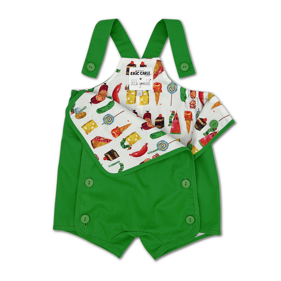 playful lining of vibrant green baby romper with adjustable shoulder straps and side button closures. The inner lining features a colorful food-themed print inspired by Eric Carle, displaying various illustration.