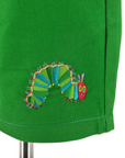 Close-up of green fabric featuring an embroidered design of the Very Hungry Caterpillar, with vibrant shades of green, blue, red, and yellow