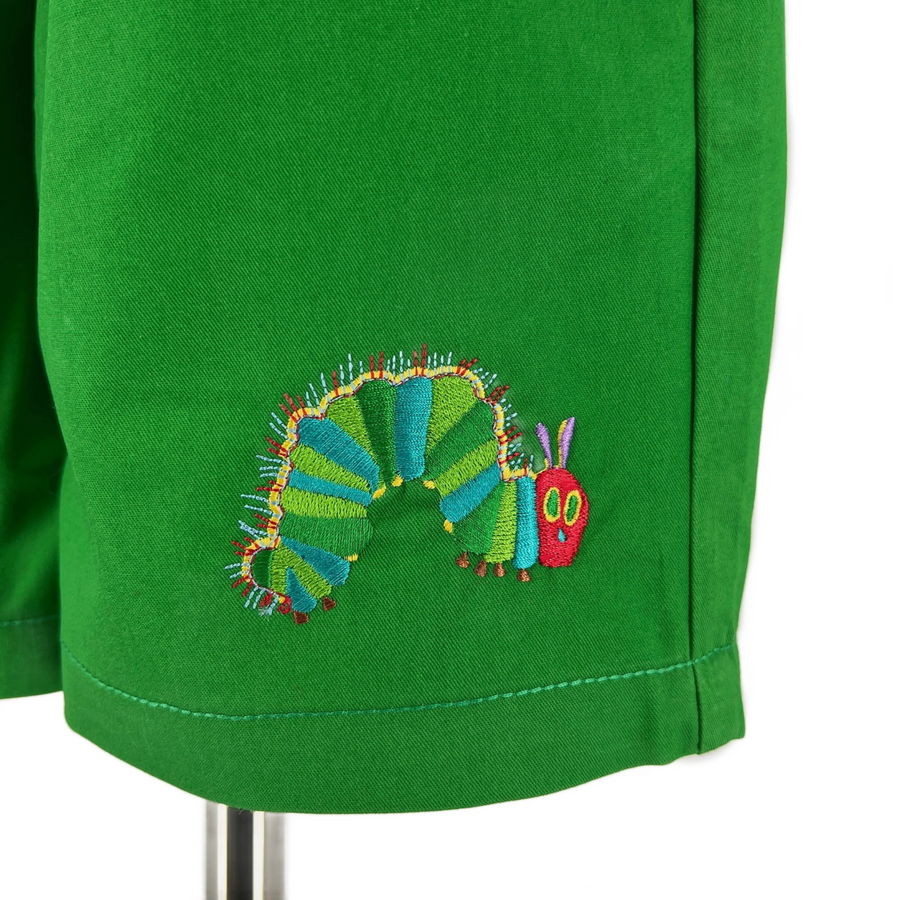 Close-up of green fabric featuring an embroidered design of the Very Hungry Caterpillar, with vibrant shades of green, blue, red, and yellow