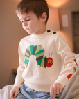 Child wearing a cozy beige knit sweater with a colorful caterpillar design, inspired by The Very Hungry Caterpillar book