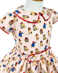 Close-up of a Paddington Bear print dress with red piping and a belt.