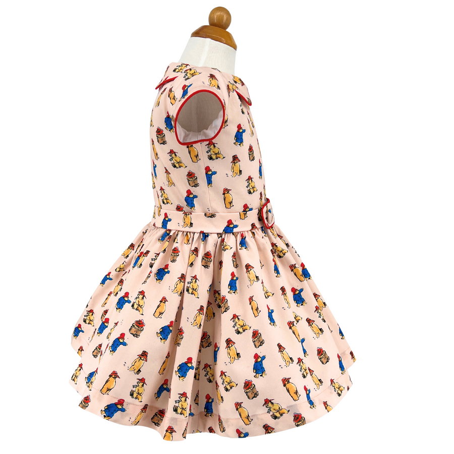 Side view of a pink Paddington Bear dress with red piping