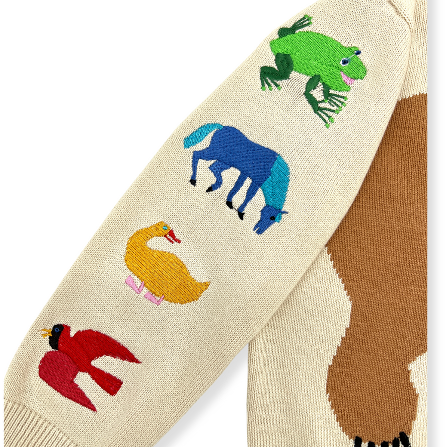 A close-up of the sleeve of a kids' sweater, highlighting intricate embroidery of a frog, horse, duck, and bird.