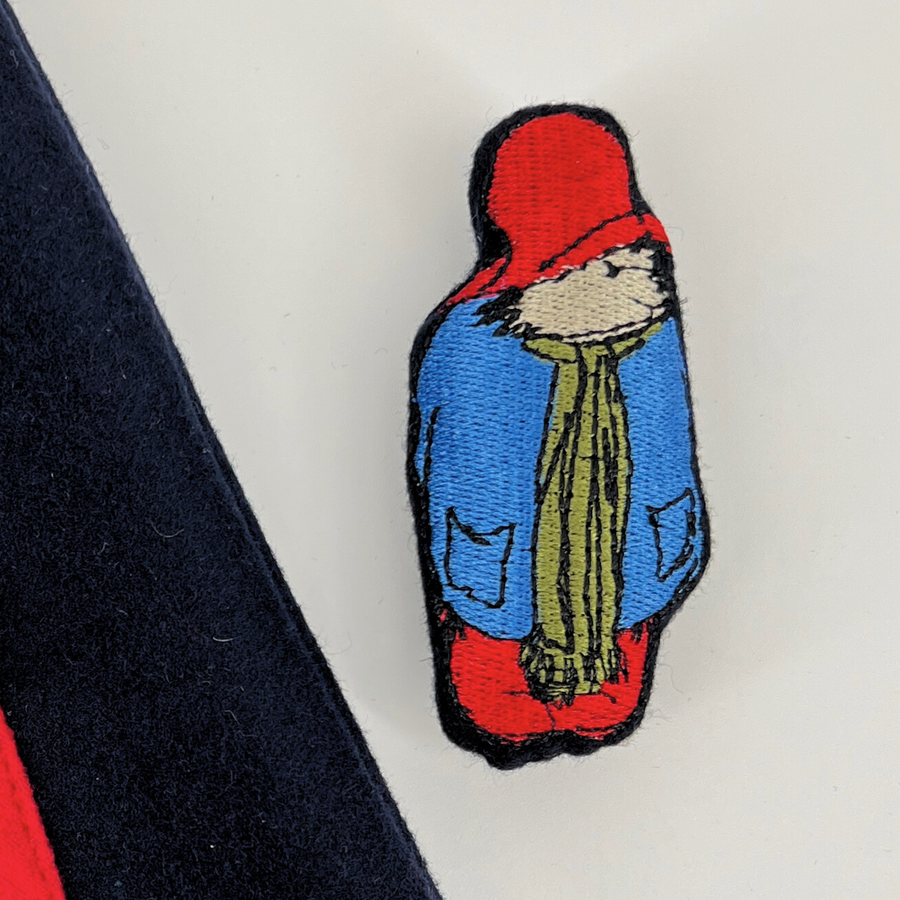 Close-up of an embroidered bear patch on a wool dress, featuring fine stitching and vibrant colors.