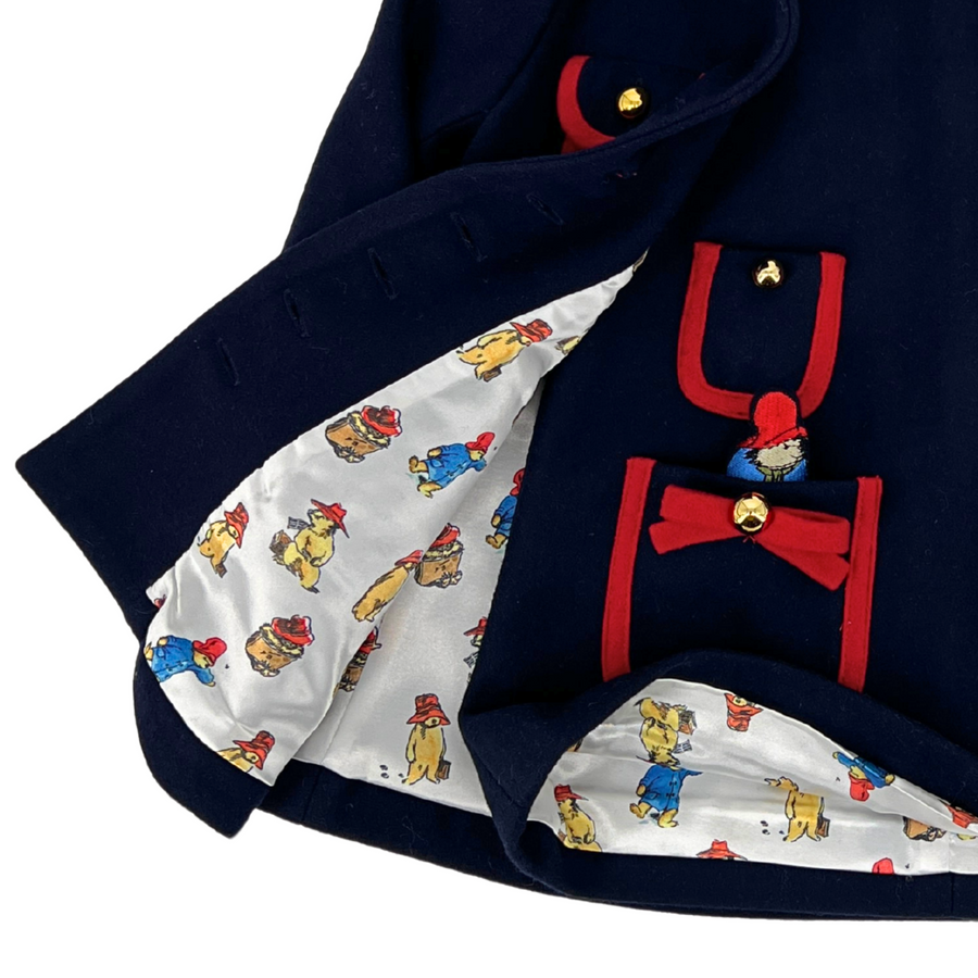 Close-up of the interior lining of a Little Goodall navy dress with red trim, featuring a playful patterned fabric and charming pocket details.