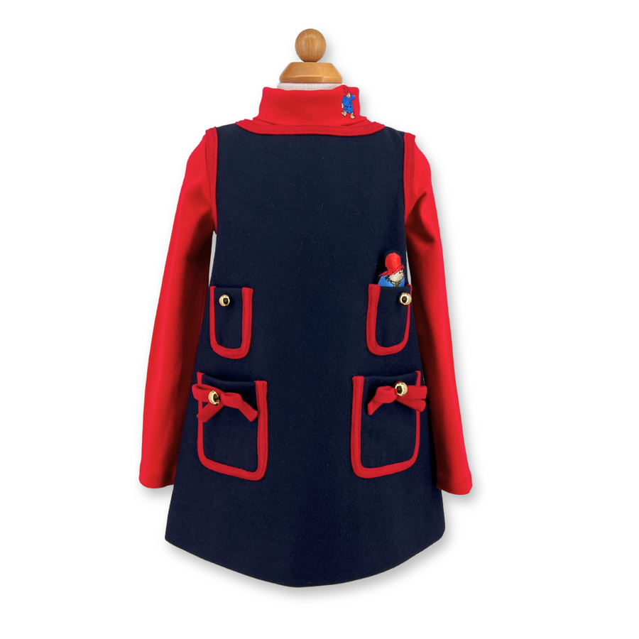 Girls' wool pocket dress with red trim, gold-tone buttons, bow details. Features four pockets and a removable embroidered bear for play. Heirloom quality