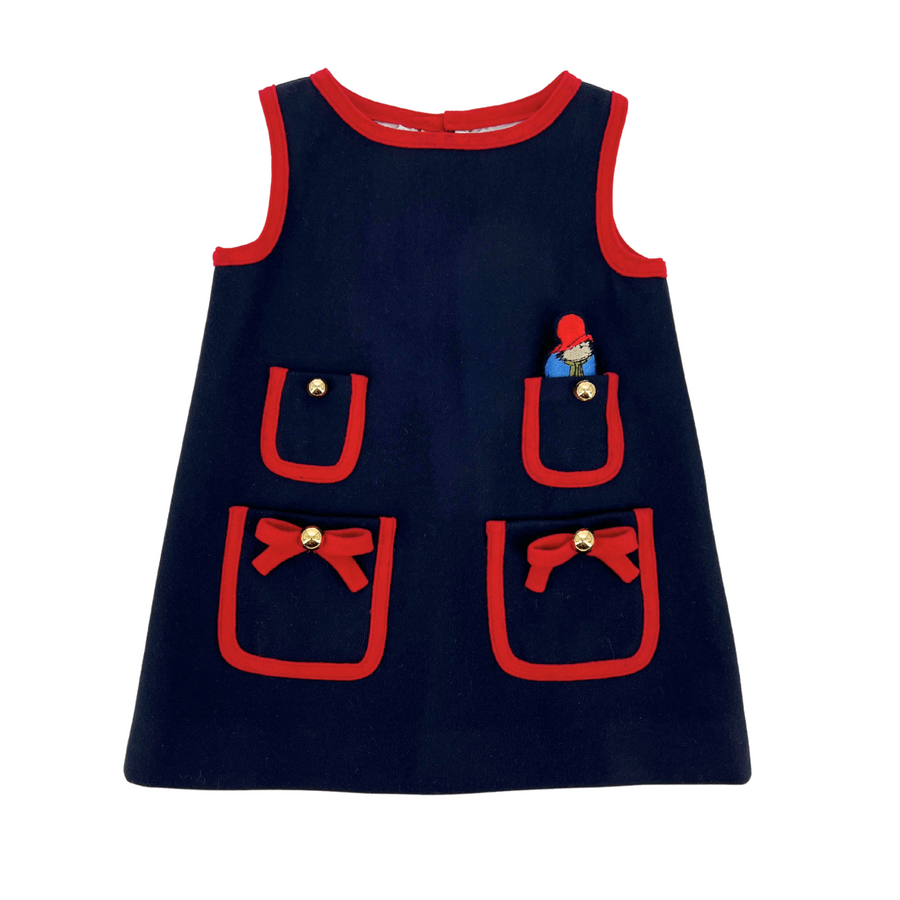 Navy blue girls' pocket dress with red trim, bow details, and a mini plush Paddington Bear