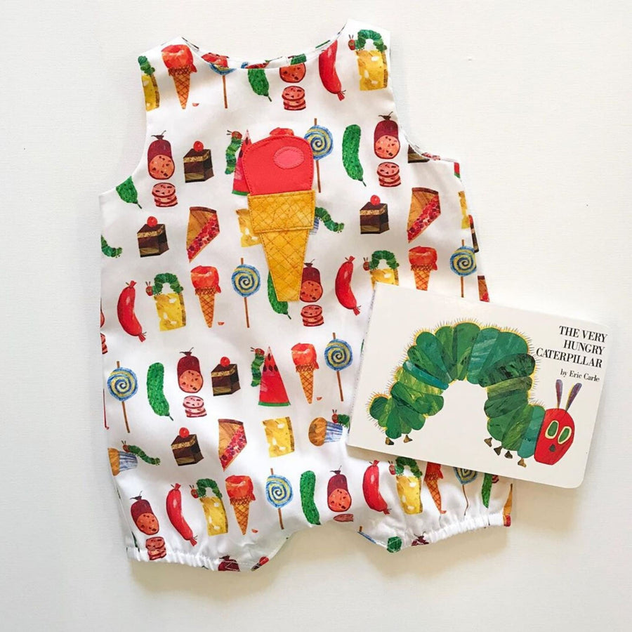 The Very Hungry Caterpillar Board Book next to a romper for boys and girls featuring colorful food illustrations inspired by the book