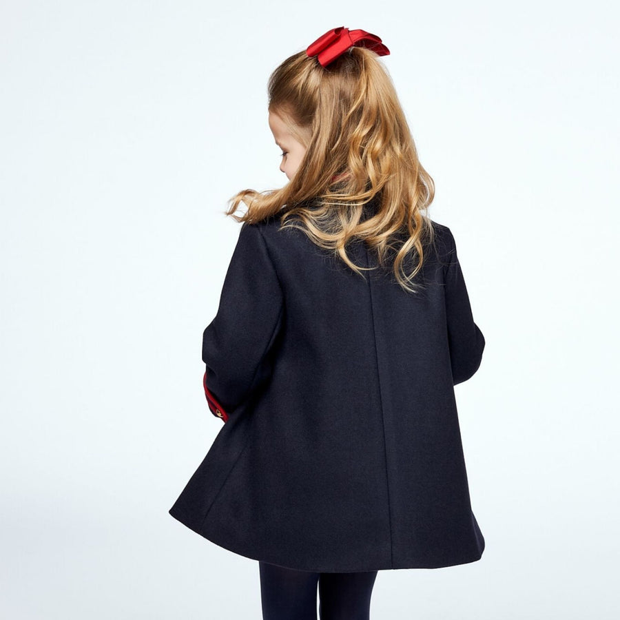 Girl in navy coat with red bow, seen from behind